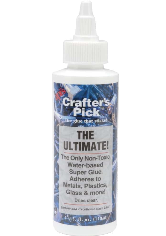 A white bottle of Crafter’s Pick The Ultimate! glue with a pointed nozzle. This non-toxic, water-based super glue is perfect for projects like easy corkboard placemats—adheres to metals, plastics, glass, and more, and dries clear.
